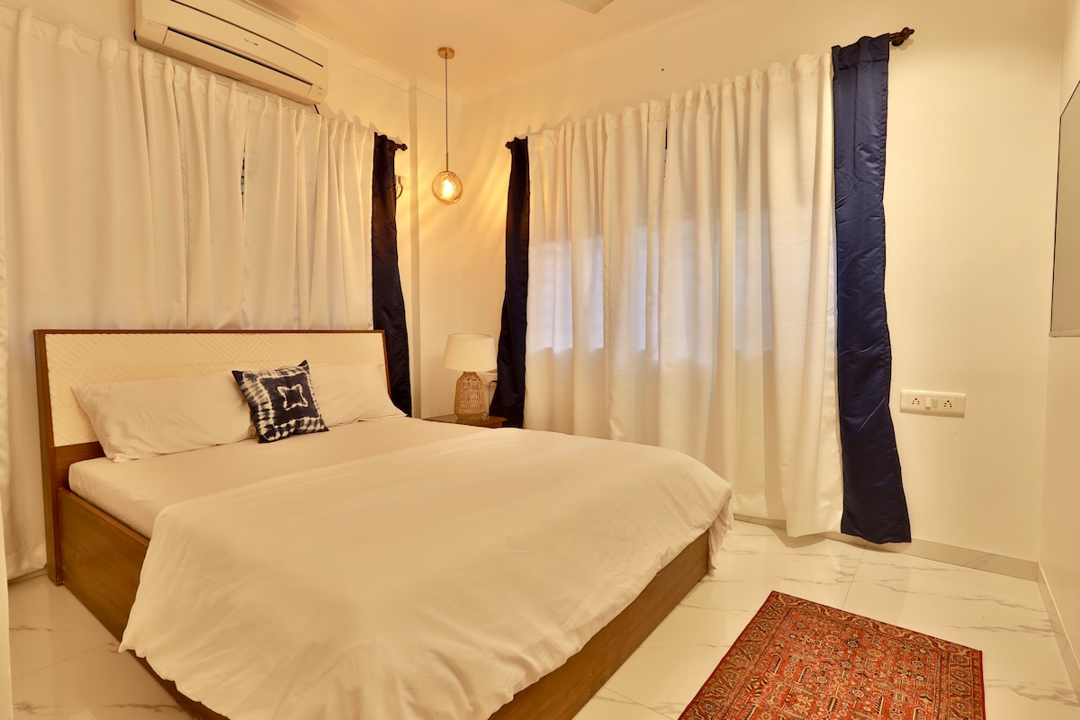 Red and indigo textiles layered across an India House bedroom
