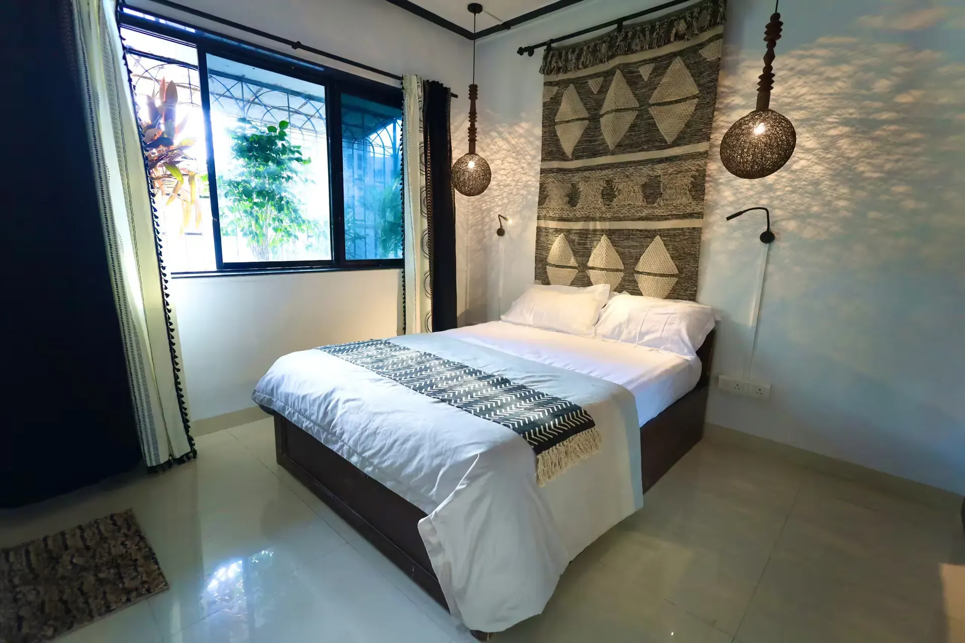 Bedroom with a patterned bed runner, a woven wall hanging and a sunny window