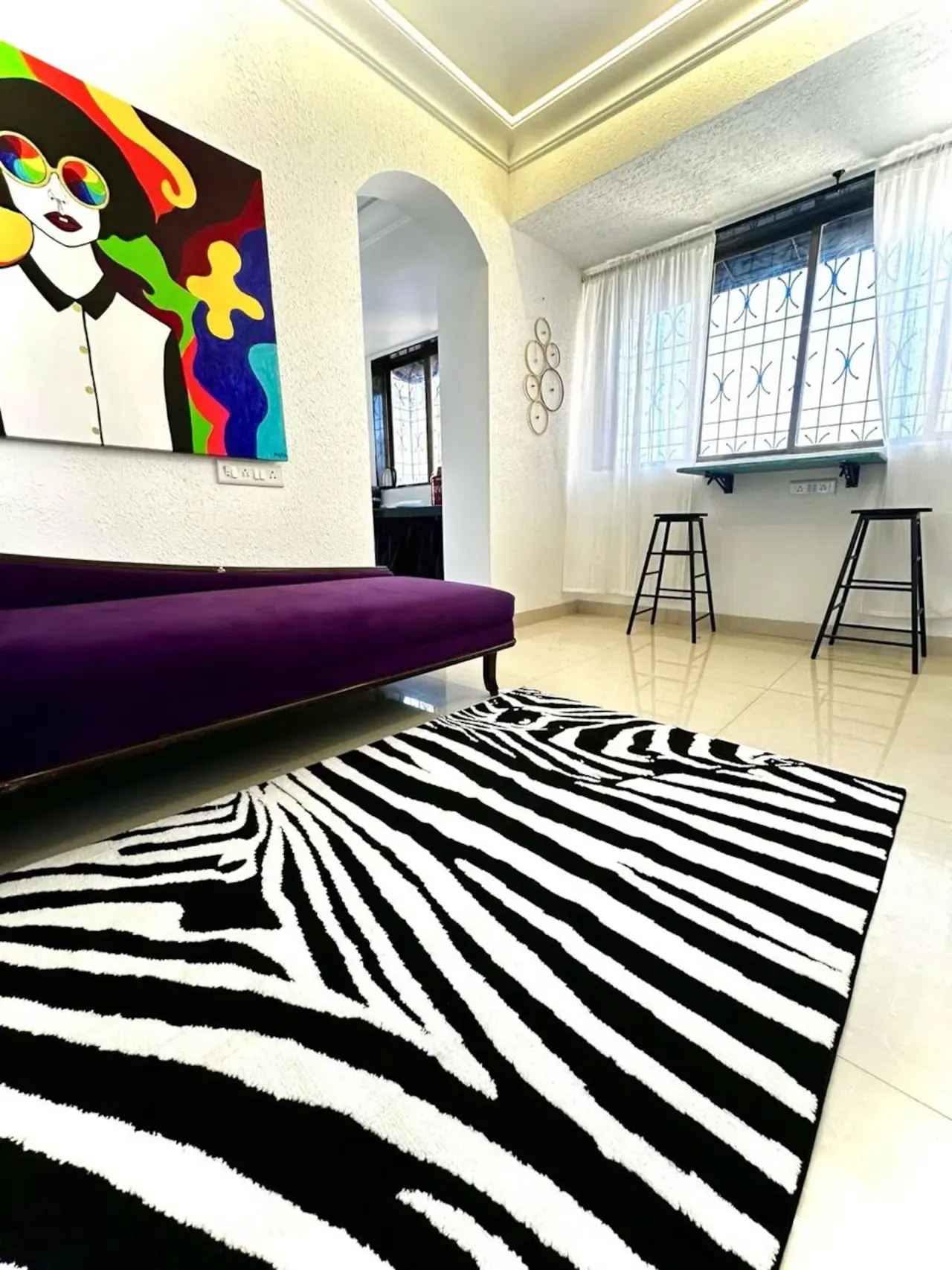 Living room with a purple daybed, a zebra-print rug and a bold pop-art canvas