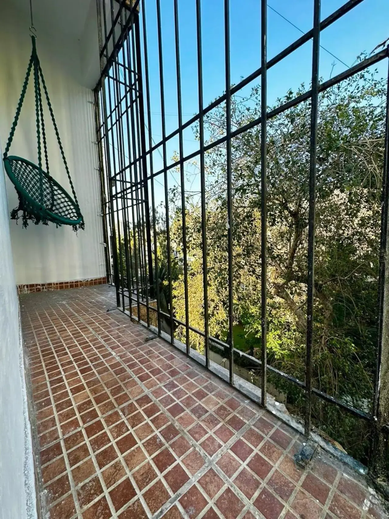 Screened passage with terracotta floor tiles and a hanging chair
