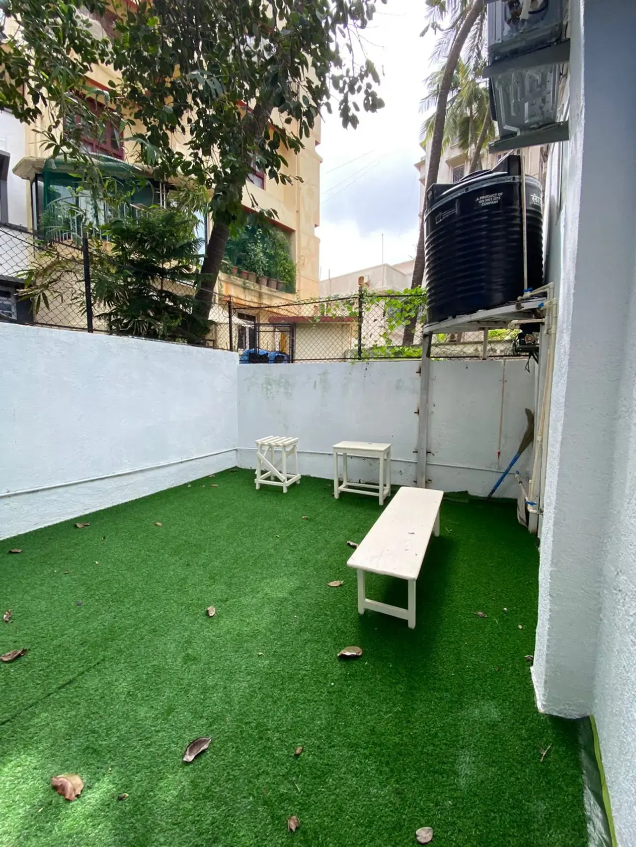 Private yard with artificial grass and a white bench