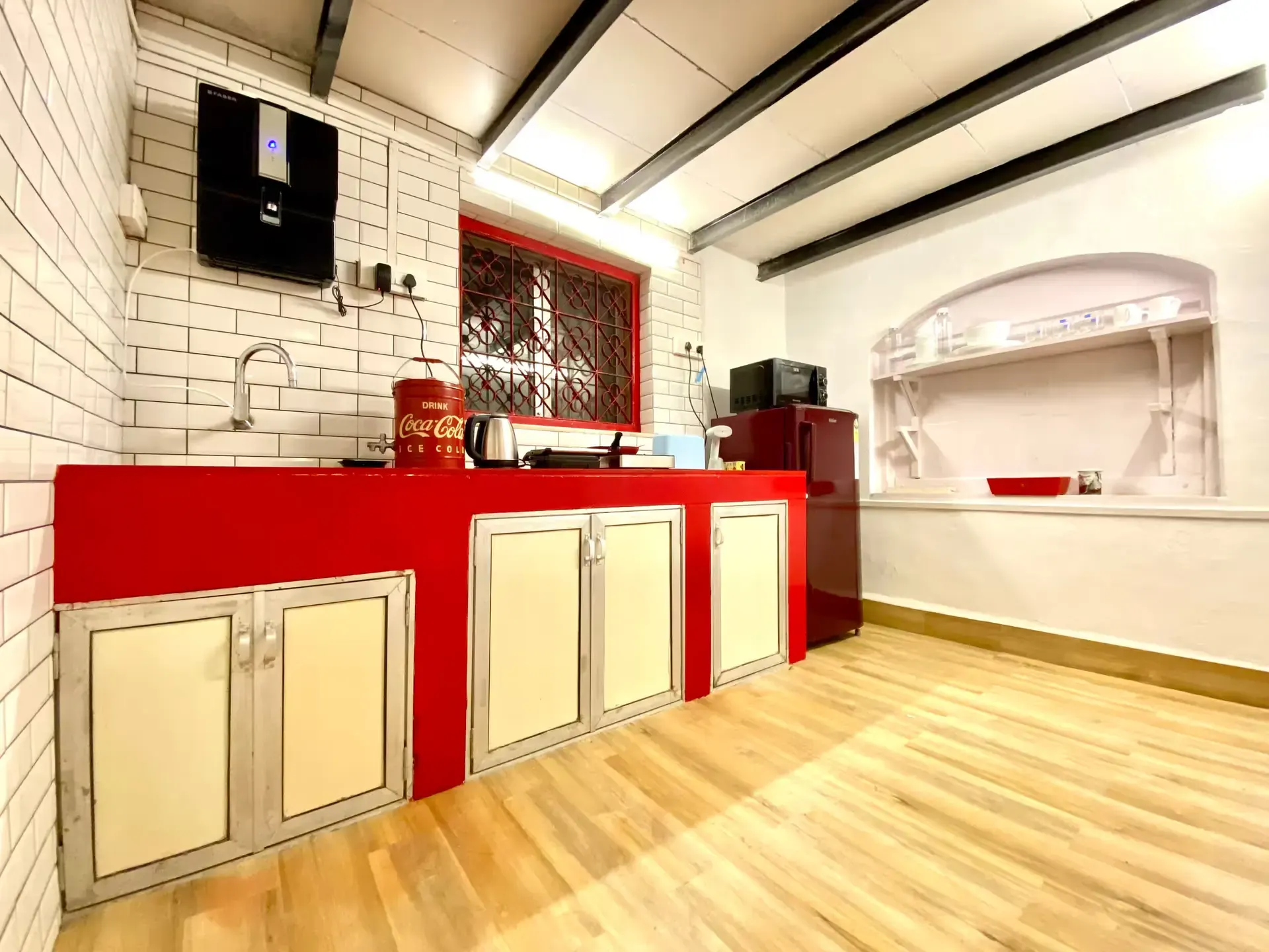 Kitchenette with red cabinets, white brick tiles and exposed beams