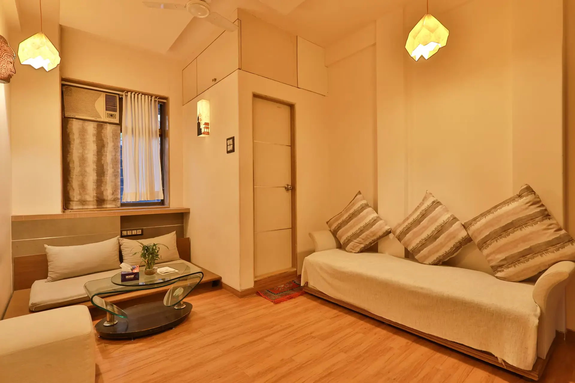 Living room with a cream sofa, a glass-top coffee table and warm wood flooring