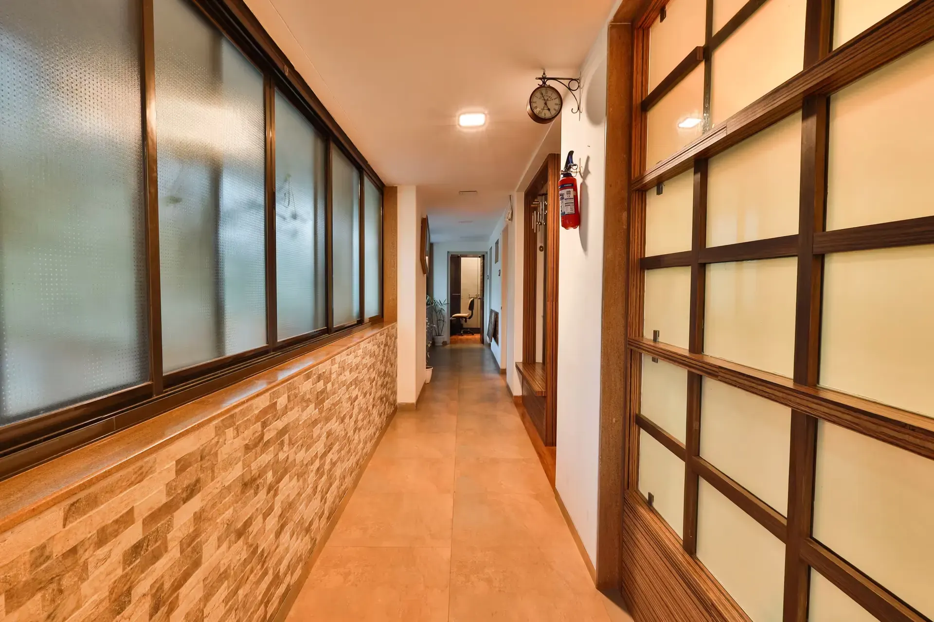 Long corridor lined with frosted-glass windows and warm timber panels