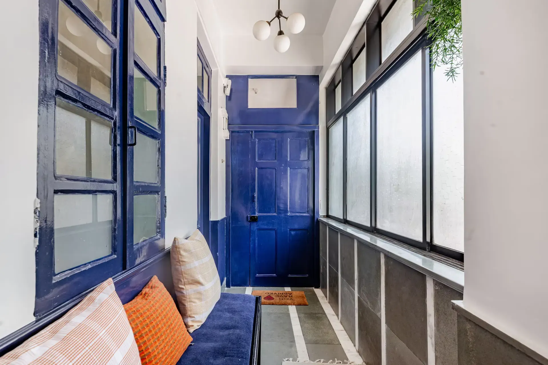 Entrance passage with a deep blue door, blue-framed windows and a cushioned bench