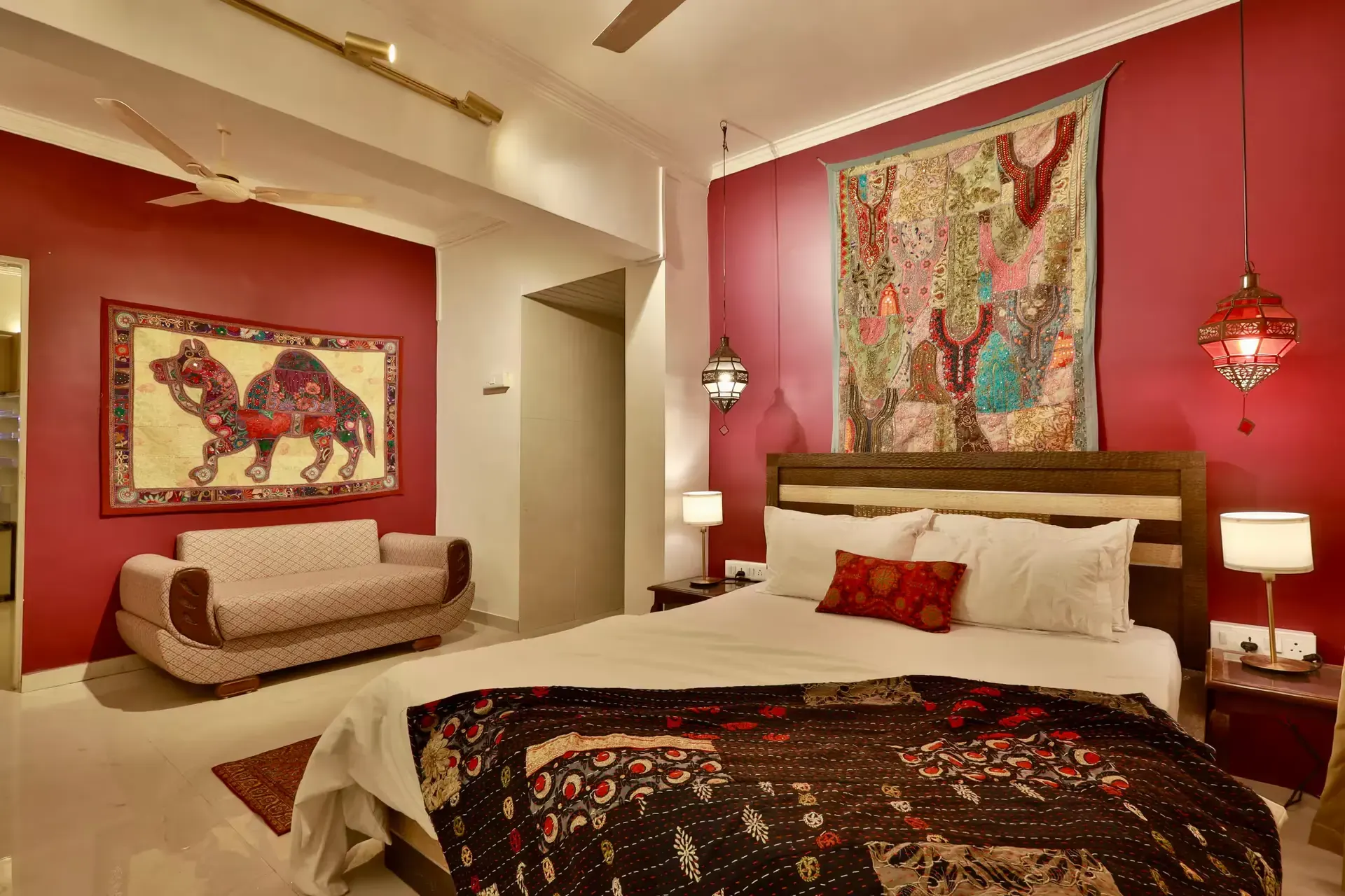 Bedroom with a crimson wall, an embroidered camel tapestry and a patterned quilt