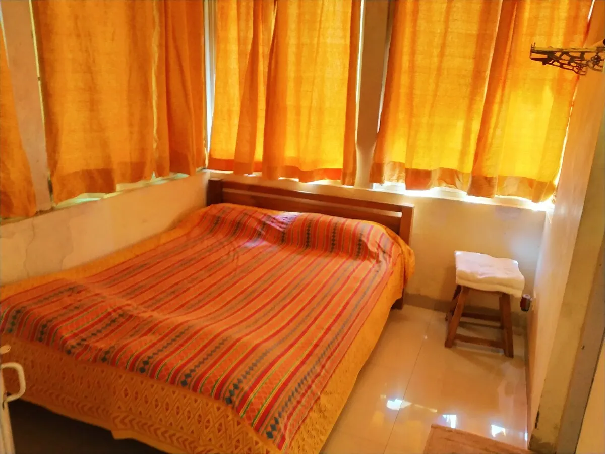 Kashid Cottage's second bedroom with warm orange curtains
