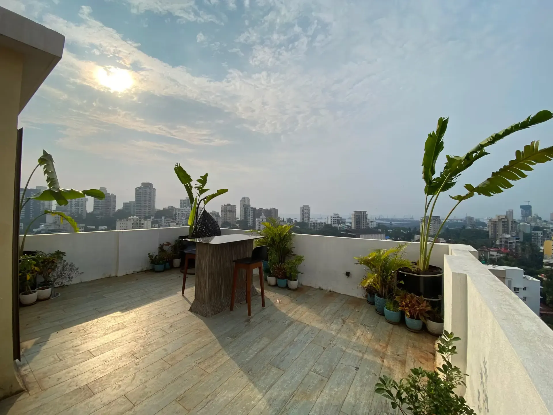 Terrace with a bar counter, potted plants and a wide view across the city