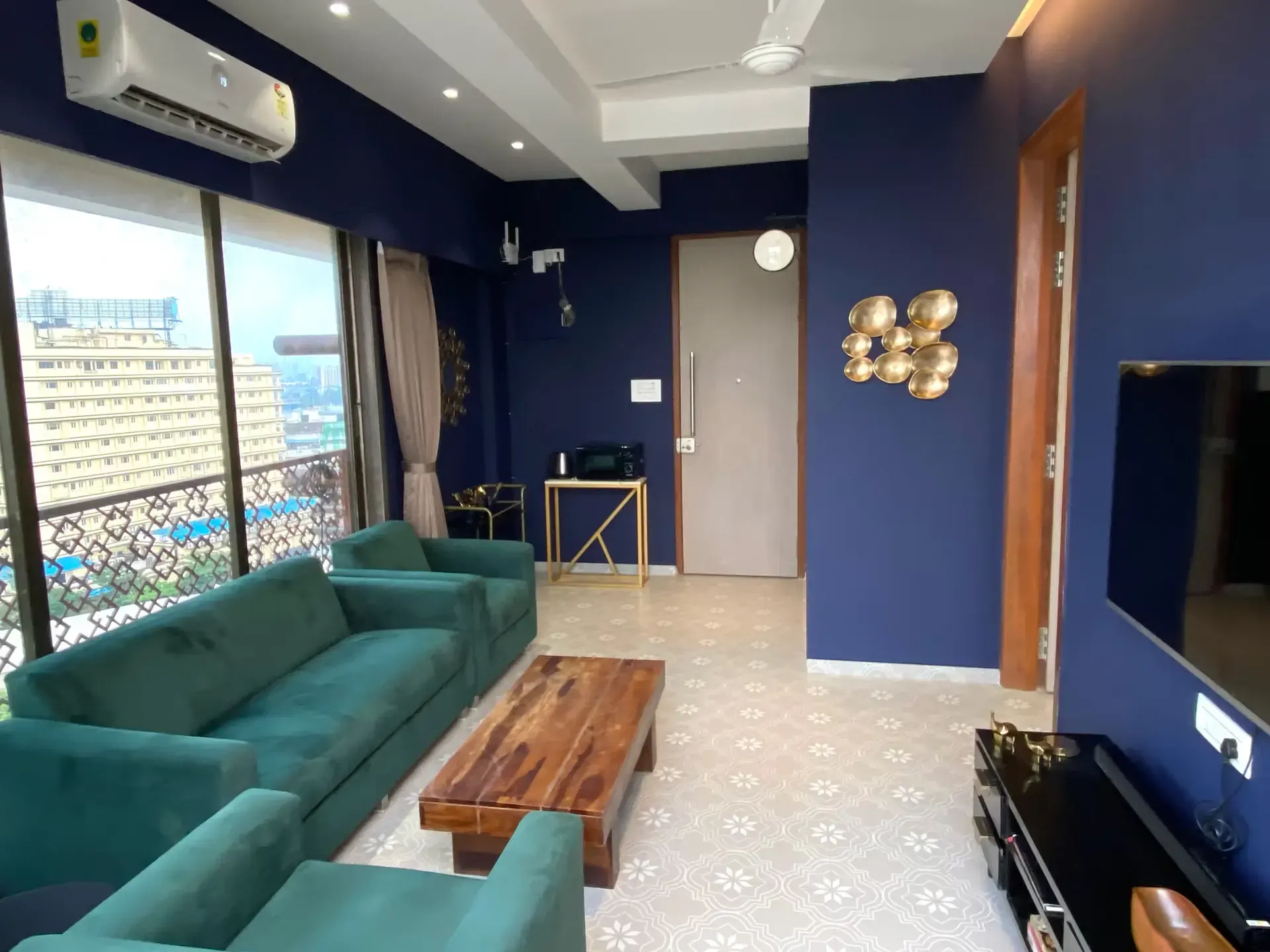 Living room with a teal velvet sofa, a wooden coffee table and deep blue walls