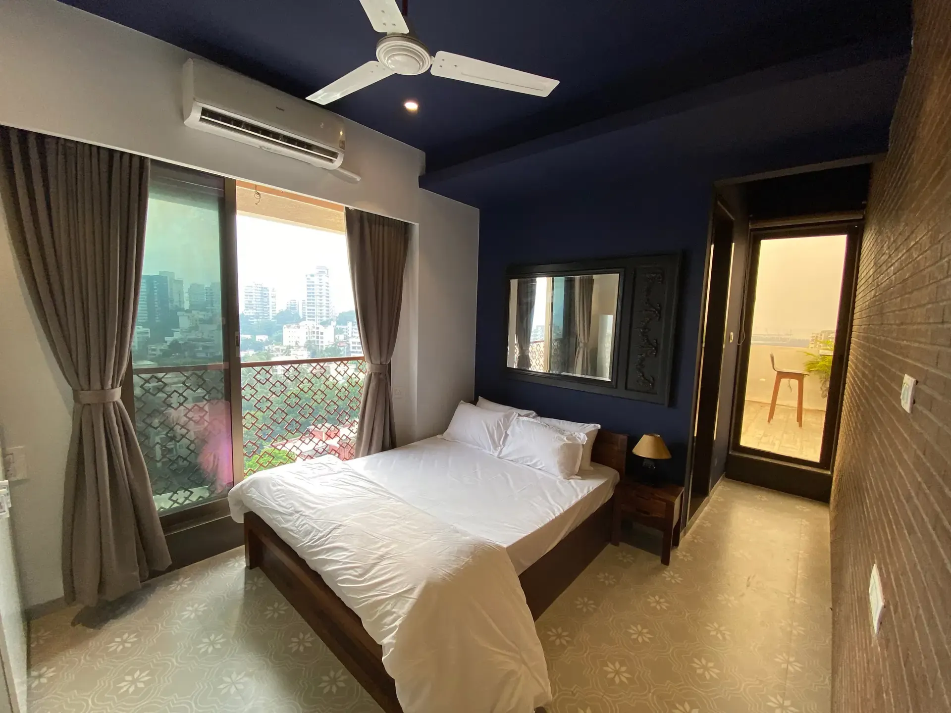 Bedroom with white bedding and a large window onto the city