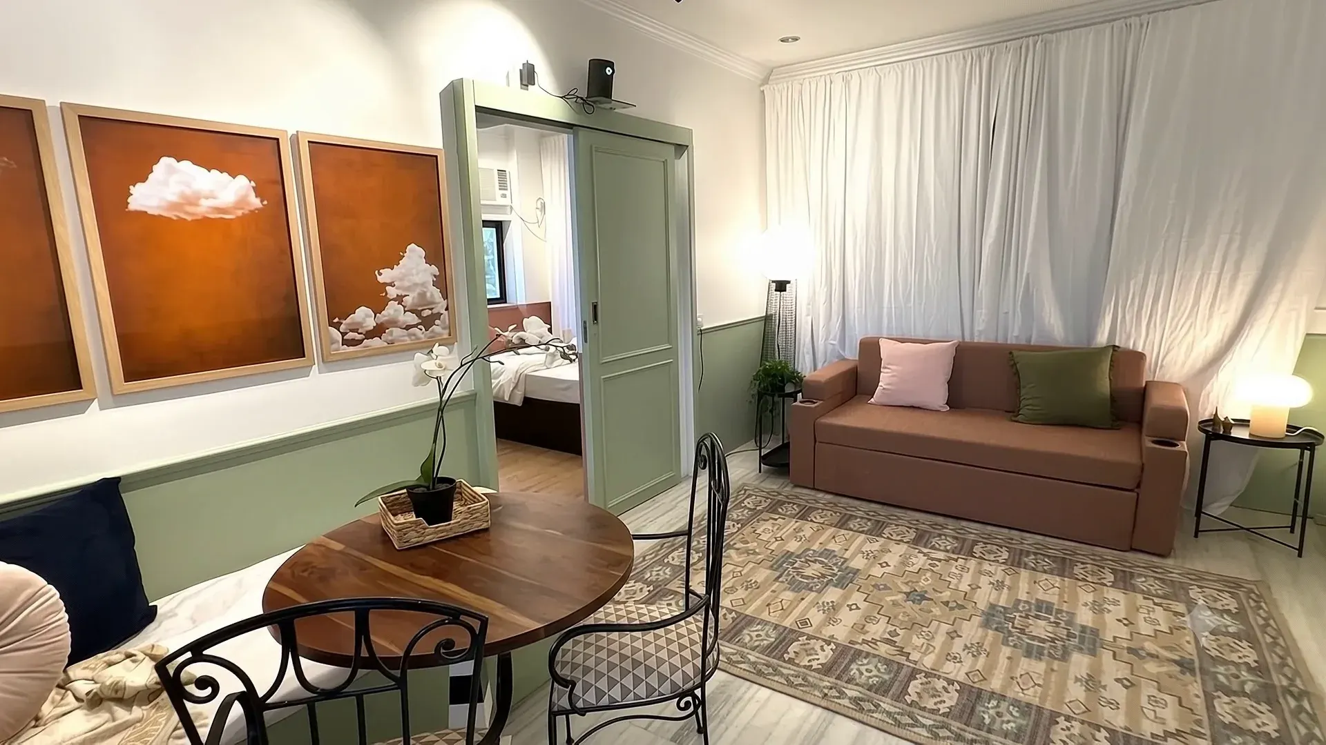 Sage-green panelling, a round table and cloud artwork inside Cloud House